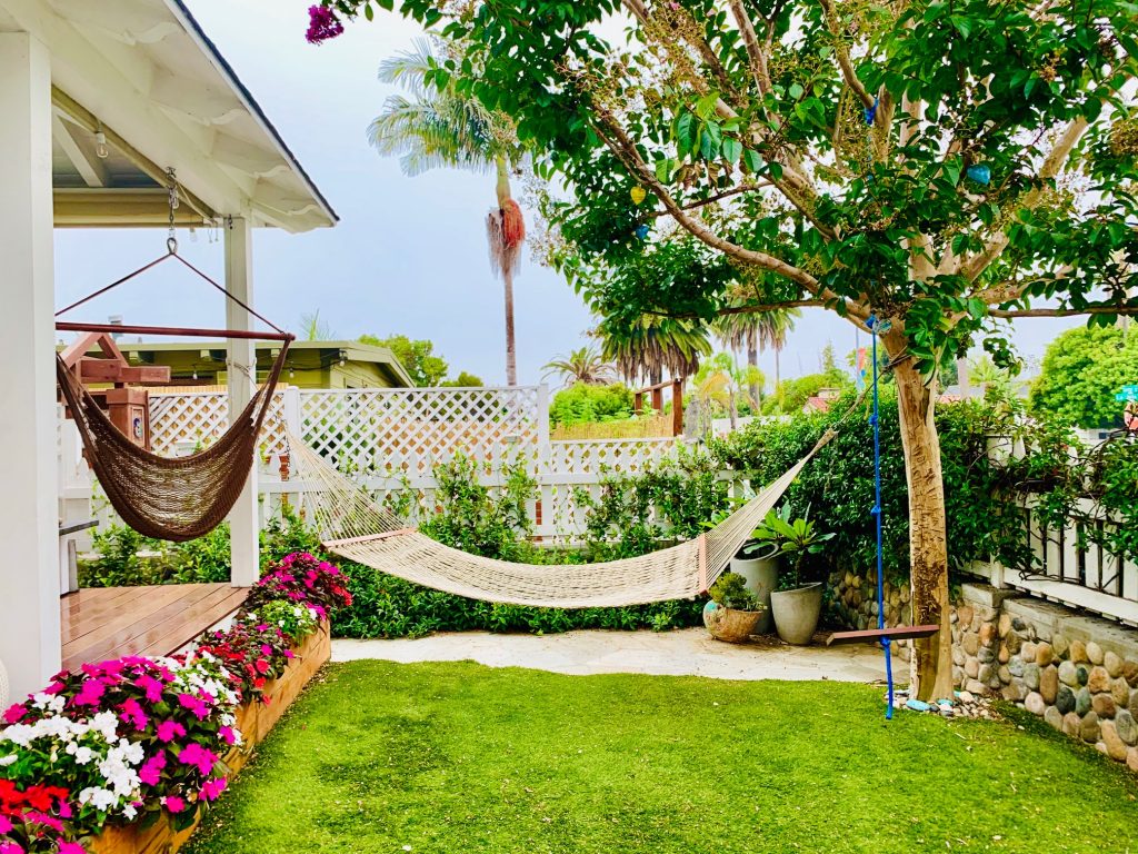A hammock in a front yard tie between a tree and house