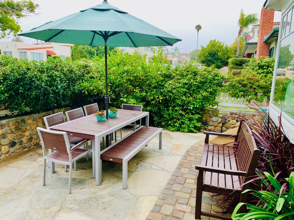 Front yard patio area with a table and chairs and a bench